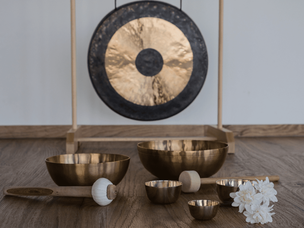 Tibetan sound bowls on a table with a gong in the back of the bowls