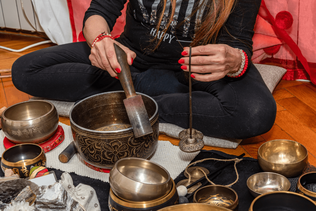 Person busy with sound bowl therapy with not a lot of space to work, having a stick in one hand sounding the bowl